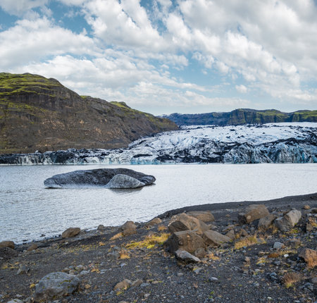 Soheimajokull picturesque glacier in southern Iceland. The tongue of this glacier slides from the volcano Katla. Beautiful glacial lake lagoon with blocks of ice and surrounding mountains.の写真素材