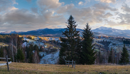 Late autumn mountain pre sunset scene with snow covered tops in far. Picturesque traveling, seasonal, nature and countryside beauty concept scene. Carpathians, Ukraine.の写真素材