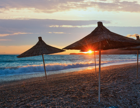 Summer sunset beach with strawy sunshades (Albania).の写真素材