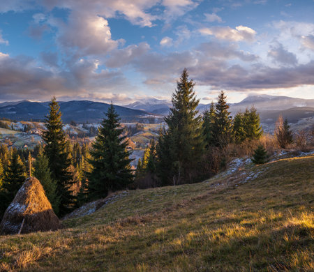 Late autumn mountain pre sunset scene with snow covered tops in far. Picturesque traveling, seasonal, nature and countryside beauty concept scene. Carpathians, Ukraine.の写真素材