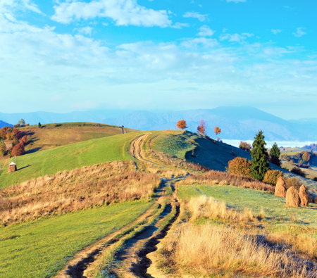 Autumn misty morning plateau with stack of hay and country road (Mighgirya village outskirts, Carpathian Mt's, Ukraine).の写真素材