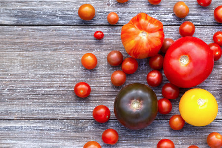 Assorted ripe colorful tomatoes on the gray wooden garden table, top view.の写真素材