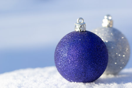 Close up of traditional blue and silver New year decoration spheres on the white snow and with blue background.の写真素材