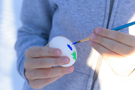 Child is painting holding an egg and painting for Easter, easy flower drawing.