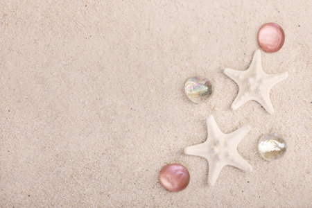 Summertime textured background with white star fish and red glass pebbles on the white sand.
