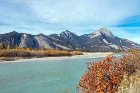 Scenic view to a mountain river with turquoise waters in fall season, yellow and orange leaf colour....