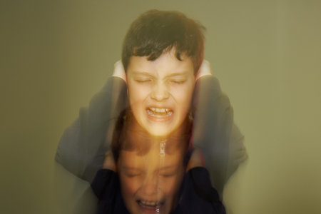 A teenager boy is holding his ears and screaming of negative emotions, anger and pain.の写真素材