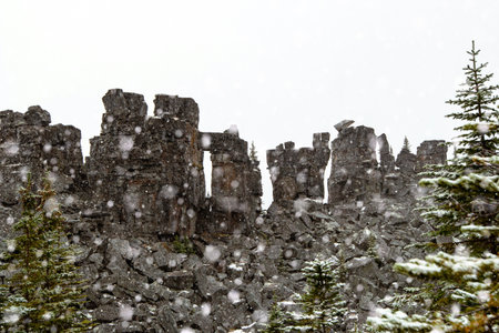 Unique rock formations and scenic view in the mountains with first snow, hiking area with green fir...