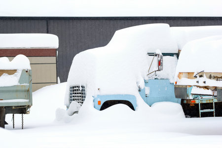 Site with old abandoned dump trucks, metal junk under heavy snow after snowfall in winter, rural landscape.の写真素材