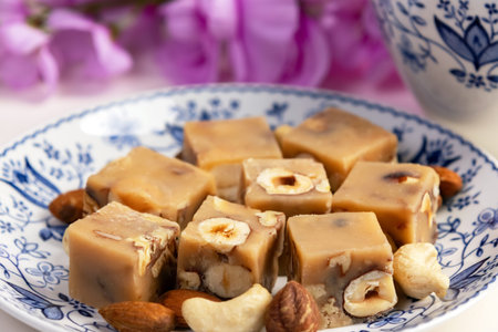 Homemade butter caramel fudge squares with hazelnuts in stylish white with blue floral decor saucer...