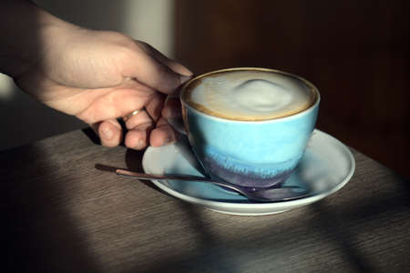 woman's hand grasping a homemade cappuccino cupの写真素材