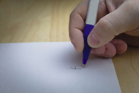 man's hand signing a contract over a desk