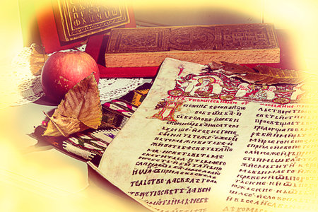 Page from Miroslav Gospel embroidered on canvas. Wood carvings, apple, leaves, crochet, and kilim. Selective focus. Post processed. Grain noise added.のeditorial素材