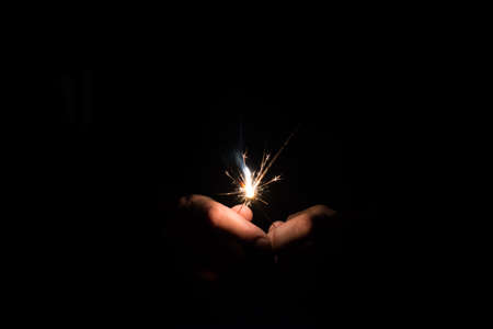 Two sparklers gathered together and emerging from the dark, are almost burned out to the end.の写真素材