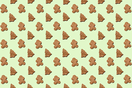 Pattern made of unbaked gingerbread man cookies and Christmas tree cookies on a vivid light green background.の写真素材