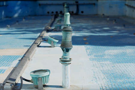 A fountain telescoping nozzle and an underwater spotlight in a fountain basin tiled with small blue...
