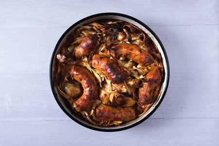 Sausage and apple bake with honeyed parsnips and caramelised onions. Variation of Jamie Oliverâs recipe. Chipolatas are replaced with homemade sausages.の写真素材