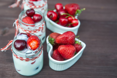 yogurt with Cherry and strawberries, square. Berries of blueberries and strawberries are scattered on the table. Cooking, healthy food, food packagingの写真素材