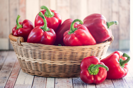 Basket with juicy red bell pepper on natural rustic backgroundの写真素材