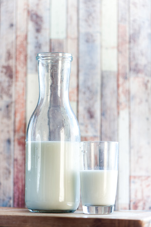 bottle of milk and a glass of milk on a natural, wooden background. Breakfast, natural rustic foodの写真素材