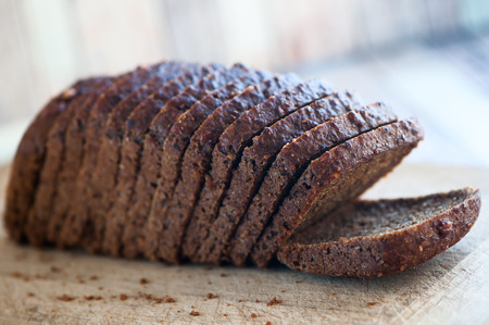 Whole-wheat bread with seeds cut on a wooden board on a natural background. Healthy food, healthy...