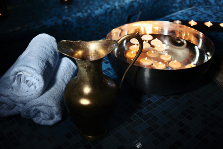 Scenery baths hammam, spa procedures. Copper jug, bowl with burning candles, white towelsの写真素材