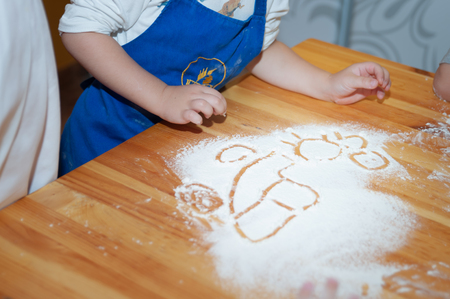 Children cook from dough and paint on flour. The concept of children's assistance in cooking foodの写真素材