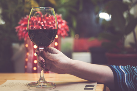 Glass of red wine in the hand of a girl, toned. Concept girl and alcoholの写真素材