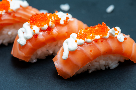 Delicious and juicy Sushi with salmon rice and caviar close-up on a black backgroundの写真素材