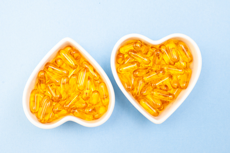 Heart-shape plate with fish oil capsules omega 3, healthy product   and   supplement  concept close up,  flat layの写真素材