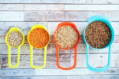 Set of different cereals in multi-colored containers, Oatmeal buckwheat, barley and rice