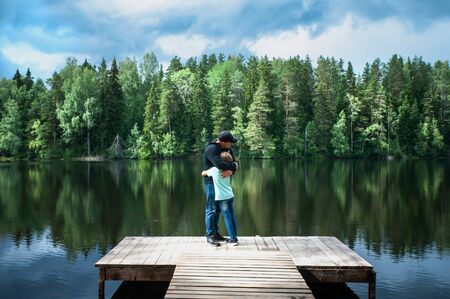 Father and his little daughter stand embracing on the pier of a beautiful lake. Father and daughter relationship concept, father's day.Family loveの写真素材