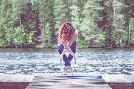 Yoga meditation  by Young yogi  girl  on the pier of a beautiful lake.  Concept of healthy life and natural balanceの写真素材