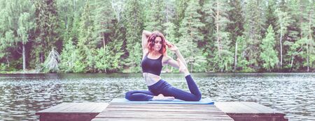 Beautiful girl in a yoga pose on the lake. Eka Pada Rajakapotasana . One Legged King Pigeon Pose . The concept of peace, healthy lifestyle. Panoramic viewの写真素材