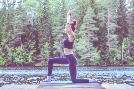Young girl practicing yoga in the nature on the lake. Female happiness. Concept of healthy life and...