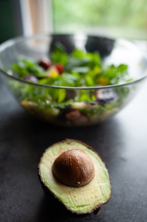 Glass bowl with fresh salad, greens, avocado and vegetables. Healthy food concept. Rustic style