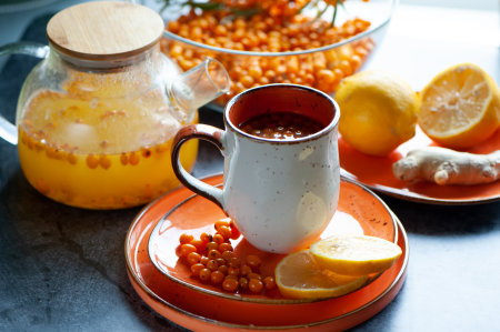 Sea buckthorn tea. Still life cup with tea, berries and lemons. Orange sea buckthorn drink, juice. Autumn mood.の写真素材