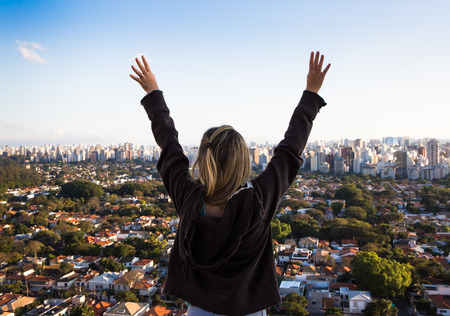Girl with wide arms open at the top of a building in Sao Paulo, Brazil.