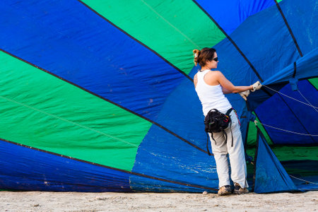 Santos, Brazil. August 8, 2009.Girl opening the mouth of the air balloon to fill it with hot airのeditorial素材