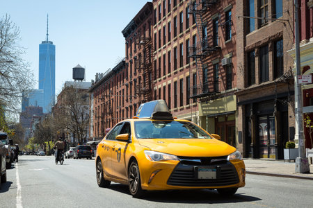 Manhattan, New York, USA. April 13, 2016. View from the intersection of La Guardia and Bleecker Street, Soho. In this photo several New York icons such as Yellow Cab, fire stairs, One World Trade Center, water box, bicycles, including a police officer finのeditorial素材