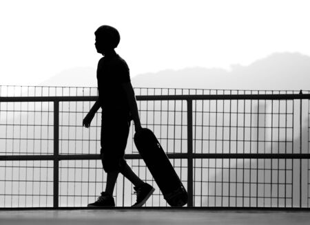 Silhouette of a skateboarder dragging his skateboard over the edge of a bowl.の写真素材