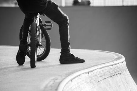 Cyclist with a BMX bike resting next to a ramp photographed in black and white.の写真素材