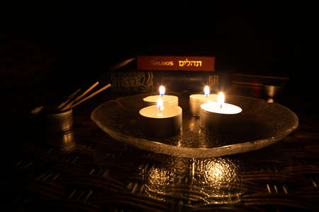 Candles lit on the day of Yom Kippur with the book of Psalms and the Bible in the background.の写真素材