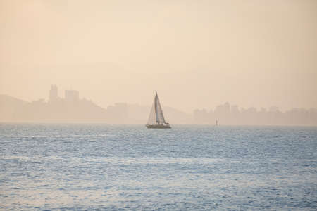 Sailboat sailing in the bay of Santos, Brazil, in a foggy and sunny day.の写真素材