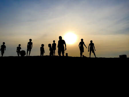 Young people playing in a sand dune on the beach during sunset.の写真素材