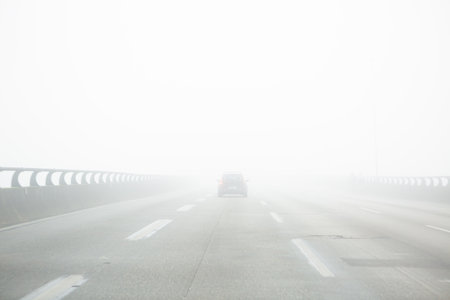 Car driving on a road on a very foggy day,