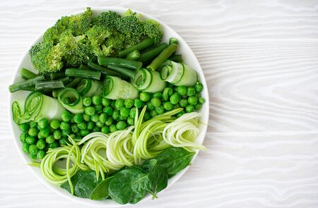 fresh green vegetables on a white plateの写真素材