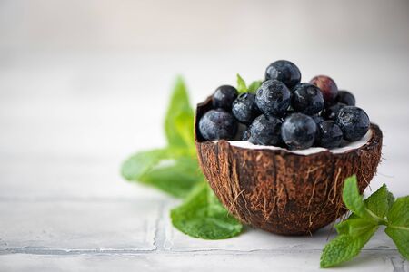 ripe blueberries with mint leaves in coconut shell on a white backgroundの写真素材