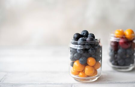 ripe blueberries and physalis berries in a glass jar on a white backgroundの写真素材