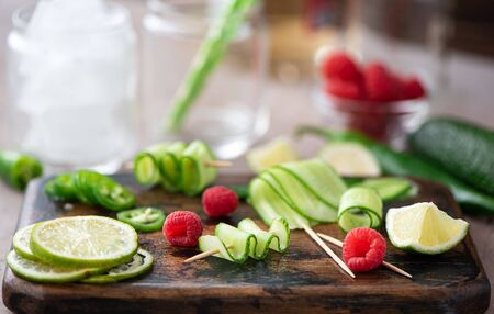 ingredients for summer cocktails - cucumbers, lime, raspberries, green chili peppers and iceの写真素材